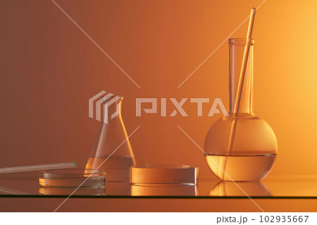 Laboratory glassware and glass rod decorated with a round transparent podium. Gradient orange background. Modern minimal showcase scene for cosmetic products promotion 102935667