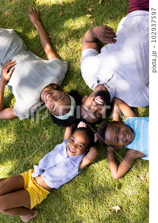 High angle view of happy african american parents and children lying on grassy land in park High angle view of happy african american parents and children lying on grassy land in park 102937597