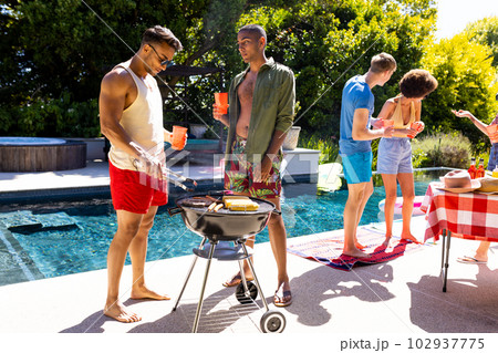 Happy diverse group of friends having pool party, barbecuing together in garden 102937775
