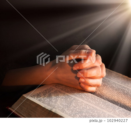 Hands clasped in prayer near an open book Hands clasped in prayer near an open book 102940227