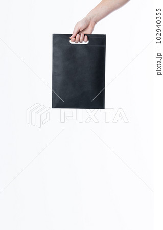 Hand of caucasian woman holding black bag with copy space on white background Hand of caucasian woman holding black bag with copy space on white background 102940355