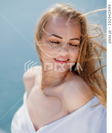 Portrait of a blond woman at the sea, a woman makes photos for memory from a trip to the sea to show to friends. Portrait of a blond woman at the sea, a woman makes photos for memory from a trip to the sea to show to friends. 102942699