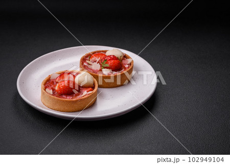 Delicious fresh sweet tartlets with strawberries and coconut flakes Delicious fresh sweet tartlets with strawberries and coconut flakes 102949104