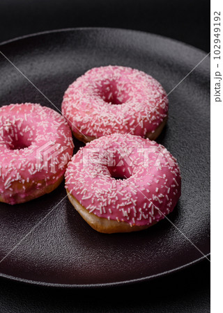 Delicious fresh sweet donuts in pink glaze with strawberry filling Delicious fresh sweet donuts in pink glaze with strawberry filling 102949192