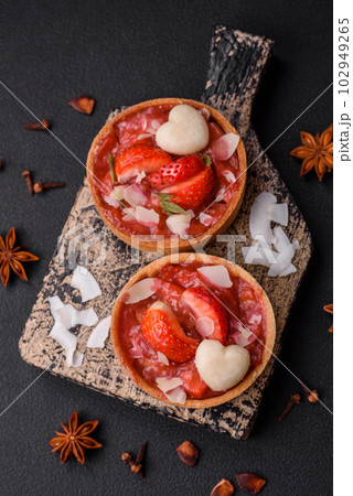 Delicious fresh sweet tartlets with strawberries and coconut flakes Delicious fresh sweet tartlets with strawberries and coconut flakes 102949265