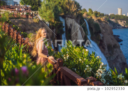 Beautiful woman with long hair on the background of Duden waterfall in Antalya. Famous places of Turkey. Lower Duden Falls drop off a rocky cliff falling from about 40 m into the Mediterranean Sea in 102952330