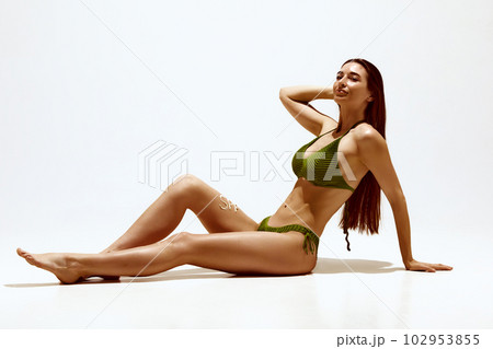 Wellness. Portrait of beautiful young woman with tanned body in swimsuit, applying spf cream against white studio background 102953855