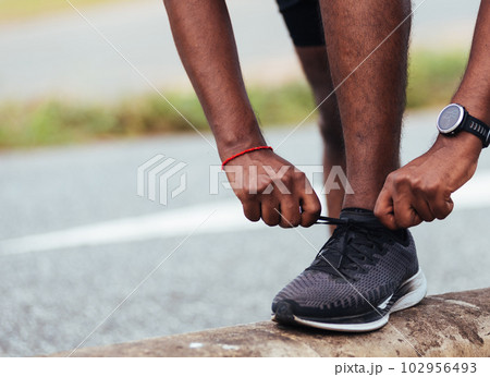 Close up Asian sport runner black man wear watch stand step on the footpath trying shoelace running shoes getting ready for jogging and run outdoor street health park, healthy exercise workout concept Close up Asian sport runner black man wear watch stand step on the footpath trying shoelace running shoes getting ready for jogging and run outdoor street health park, healthy exercise workout concept 102956493