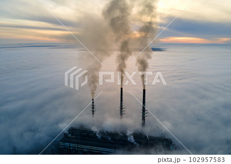 Aerial view of coal power plant high pipes with black smoke moving up polluting atmosphere at sunset 102957583