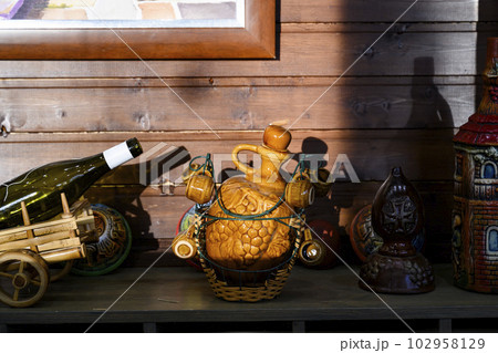 Clay jugs of wine on a wooden shelf in the sunset 102958129