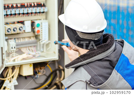 Instrumentation and automation engineer in white hard hat checks equipment. Real workflow. Back view Instrumentation and automation engineer in white hard hat checks equipment. Real workflow. Back view 102959170