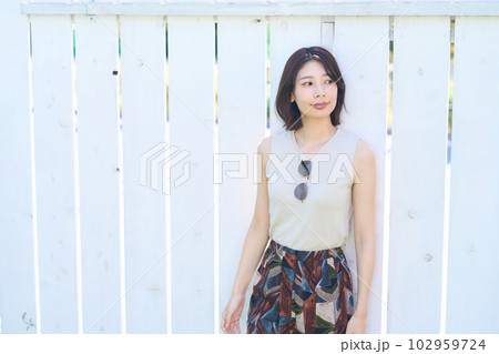 フェンスの前に立つ若い女性 102959724