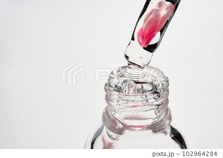 Serum bottle and pipette with rose petal close-up. Floral cosmetic product, selective focus 102964284