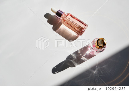 Cosmetic product bottles with rose petals and hard shadow. Skincare beauty product concept 102964285