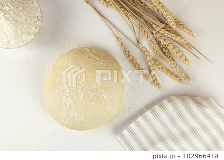 Raw dough, flour and ears of wheat on white background, top view. Home baking concept. Raw dough, flour and ears of wheat on white background, top view. Home baking concept. 102966418