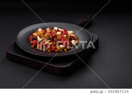 Mix of roasted cashews, hazelnuts and walnuts with dried cranberries and raisins 102967214