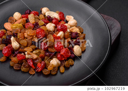 Mix of roasted cashews, hazelnuts and walnuts with dried cranberries and raisins 102967219