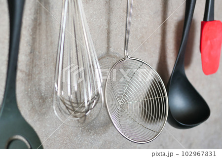 kitchen utensils hanging on gray background. kitchen utensils hanging on gray background. 102967831
