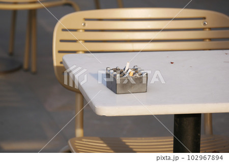 Close up burning cigarette in ashtray on table Close up burning cigarette in ashtray on table 102967894