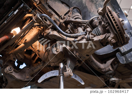 Inspects suspension, steering parts, tie rod ends. Car on a repair stand. Technical service station for car. Inspects suspension, steering parts, tie rod ends. Car on a repair stand. Technical service station for car. 102968417