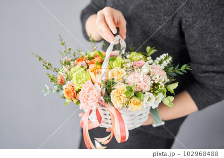 Small flower shop and Flowers delivery. Flower arrangement in Wicker basket. Beautiful bouquet of mixed flowers in woman hand. Handsome fresh bouquet. 102968488
