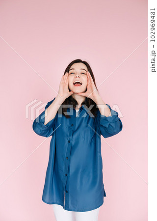 Expressive Joy: Close-Up Portrait of a Cheerful Young Woman's Hands near Open Mouth, Conveying 102969481