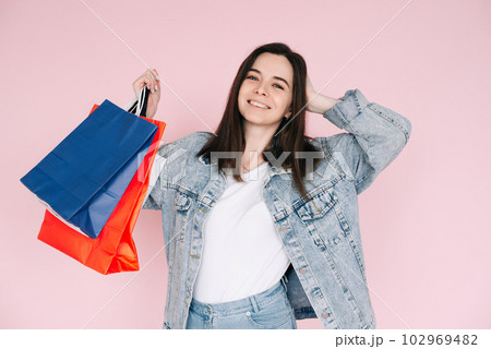 Joyful Shopper: Young Woman in Denim Shirt Celebrating, Arm Raised in Excitement, Against Pink 102969482