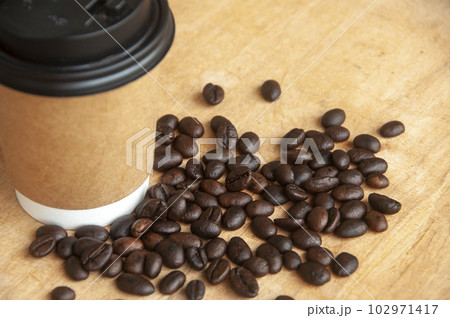 Takeaway coffee cup surrounded with coffee beans with customizable space for text or ideas. Copy space and coffee concept 102971417
