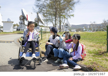 車いすに乗った女の子と学校の遠足に行く小学生の友達 車いすに乗った女の子と学校の遠足に行く小学生の友達 102971987