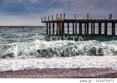 Storm in the Mediterranean Sea, Turkey, strong waves near the old wooden pier Storm in the Mediterranean Sea, Turkey, strong waves near the old wooden pier 102975973