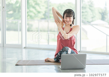 オンラインヨガ教室をするヨガ講師・ヨガインストラクターの女性（牛の顔のポーズ） 102977377