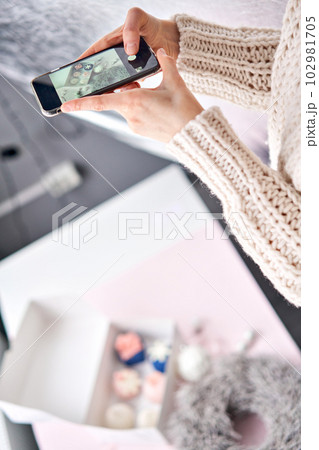 Woman with a mobile phone, takes a photo to confirm the order. Accepts an online order for of sweet delicious cakes delivery. Responds to messages in social networks and online messengers. Variety of 102981705