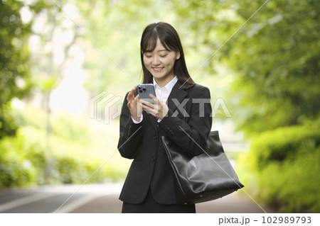 スマホを見るリクルートスーツの若い女性 スマホを見るリクルートスーツの若い女性 102989793
