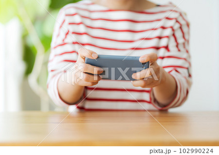 スマホを持つ女性の手元カット スマホを持つ女性の手元カット 102990224