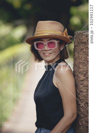 pretty woman wearing straw hat toothy smiling with happiness standing outdoor 102991117
