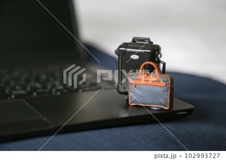 ノートパソコンの上のスーツケースとビジネスバッグ ミニチュア