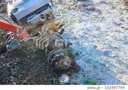 There is farmer plows ground in garden with tiller block using motor cultivator There is farmer plows ground in garden with tiller block using motor cultivator 102997794