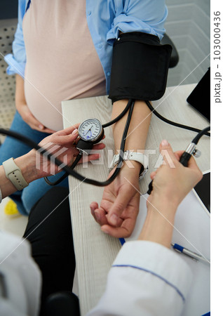 Early diagnostic, prevention and treatment of hypertension, pre-eclampsia and eclampsia in pregnancy. Close-up of obstetrician doctor, gynecological nurse measuring blood pressure of pregnant woman Early diagnostic, prevention and treatment of hypertension, pre-eclampsia and eclampsia in pregnancy. Close-up of obstetrician doctor, gynecological nurse measuring blood pressure of pregnant woman 103000436