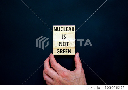 Nuclear is not green symbol. Concept words Nuclear is not green on wooden blocks. Businessman hand. Beautiful black table black background. Nuclear is not green business concept. Copy space. 103006292