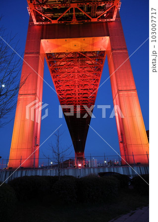 夕暮れ時に赤く光る若戸大橋 103007717