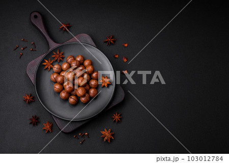 Delicious roasted macadamia nuts in shell on a dark textured background 103012784