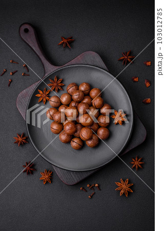 Delicious roasted macadamia nuts in shell on a dark textured background 103012785