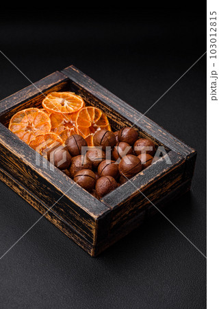Delicious roasted macadamia nuts in shell on a dark textured background Delicious roasted macadamia nuts in shell on a dark textured background 103012815