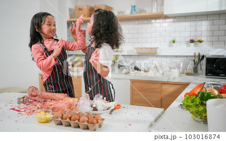 Child making cake with family, Family having fun together in kitchen 103016874