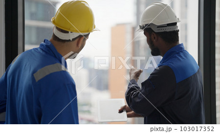 Contractor with safety helmet brainstorming with electrician technician 103017352
