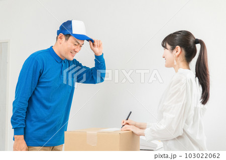 荷物を届ける配達員の男性と受け取る・サインする女性 荷物を届ける配達員の男性と受け取る・サインする女性 103022062