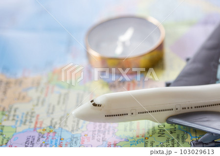 Close up the white toy airplane on the world map and blurred compass background. 103029613