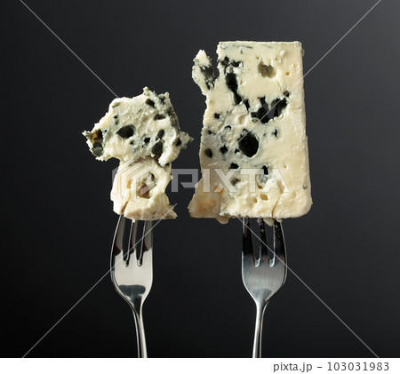 Blue cheese slices on forks. 103031983