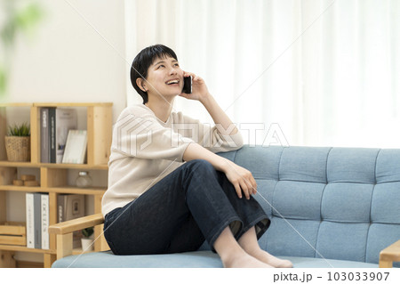 ソファーに座り電話をする若い女性 103033907