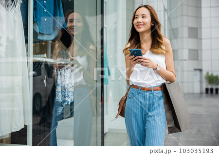 A person walking in the city, lost in her smartphone screen. She is browsing the internet, connecting with the global cyber world around her. A person walking in the city, lost in her smartphone screen. She is browsing the internet, connecting with the global cyber world around her. 103035193